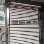 A worker operates the motor to open an aluminum high-speed rolling garage door.