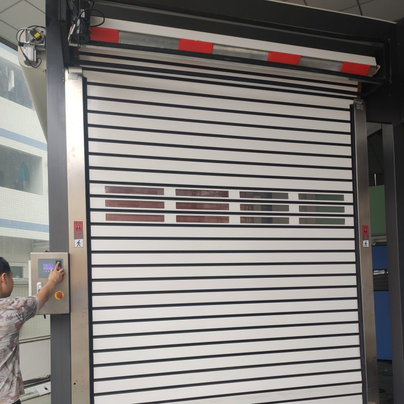 A worker operates the motor to open an aluminum high-speed rolling garage door.