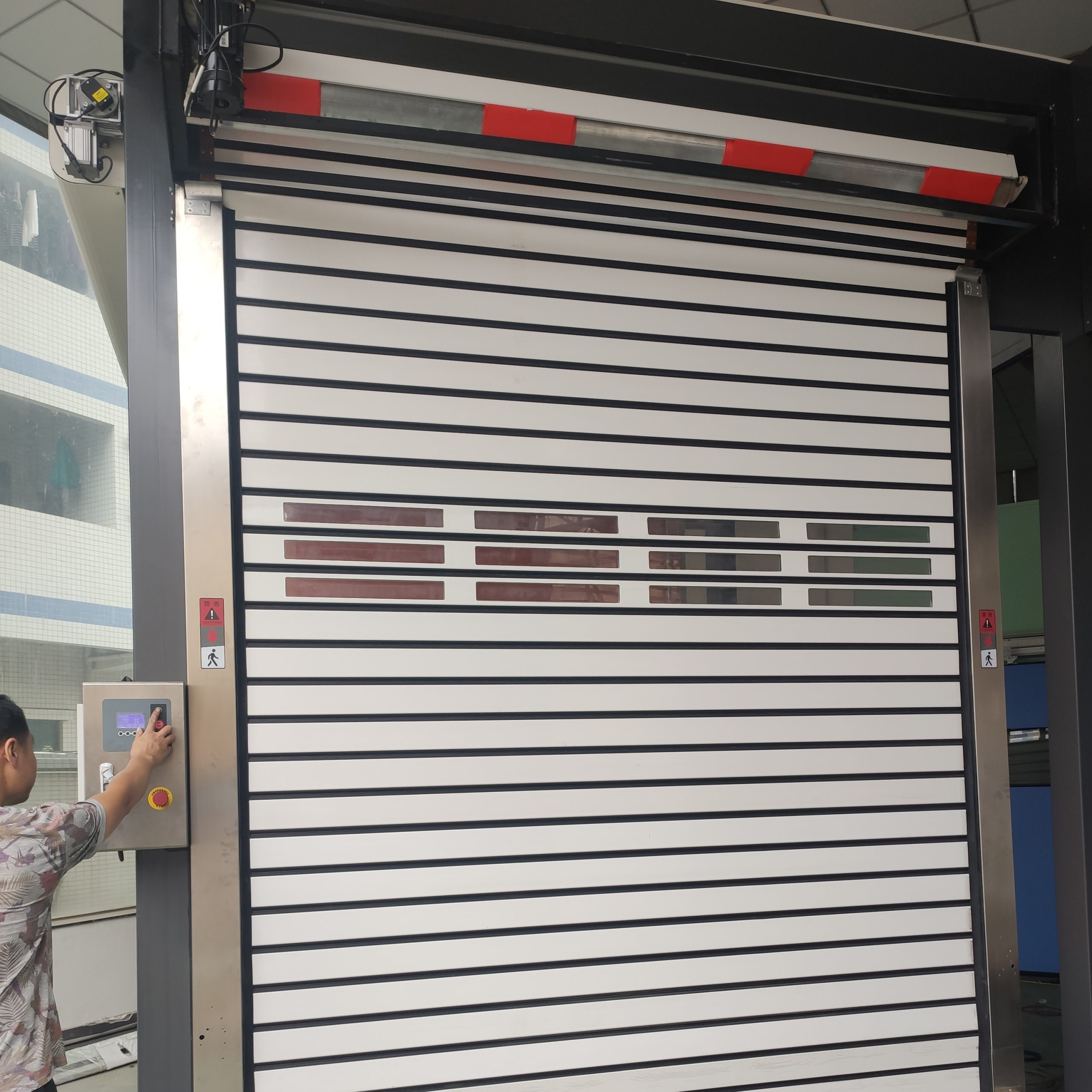 Industry Fast Rolling Doors Manufacture A worker operates the motor to open an aluminum high-speed rolling garage door.